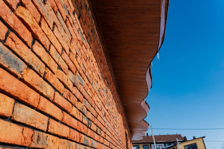 This closeup of a worn brick wall showcases each brick against a bright blue sky, highlighting...