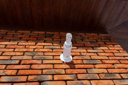 A white pipe is resting on top of a sturdy brick wall, creating an interesting contrast against the rugged texture of the brickwork that is used as a building material in constructionの写真素材