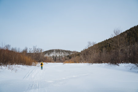 A person is skillfully riding on a beautifully snowy road that winds through the winter landscape,...