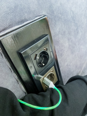 A vibrant green electrical cord is securely plugged into a wall outlet, signaling that it is fully...