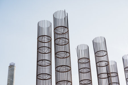A long and robust row of durable metal pipes stands prominently against a vibrant clear blue sky, showing the striking contrast between industrial materials and the inherent beauty of natureの写真素材