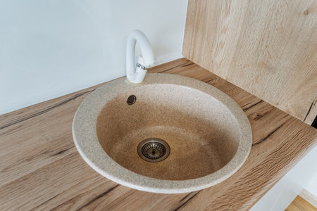 A beautifully crafted round sink is elegantly placed atop a strong wooden counter, striking a perfect balance between functionality and aesthetic charm in the overall design of the spaceの写真素材