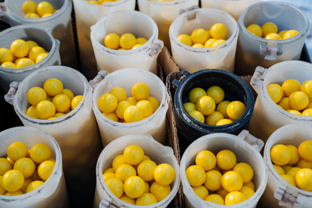 A collection of colorful plastic cups, each filled to the brim with vibrant yellow balls that...