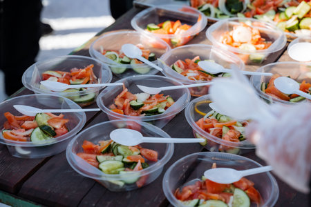 A table elegantly adorned with a variety of colorful plastic bowls, each filled with fresh vegetables and accompanied by spoons for easy serving and enjoyment of these healthy ingredientsの写真素材