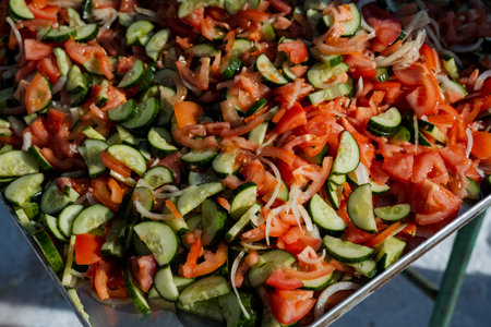 A metal tray filled with tomatoes , cucumbers , and onionsの写真素材