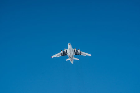 A white airplane gracefully soars through the expansive, clear blue sky on a bright day, symbolizing...