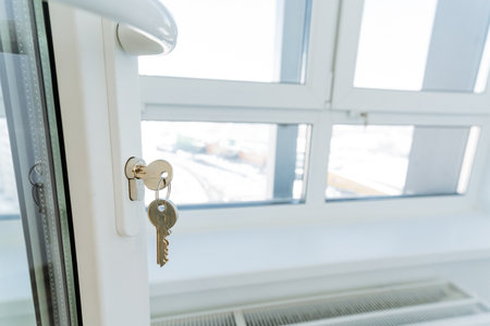 A key is dangling from a keyhole that is situated on a window . This scenario presents an intriguing visual with an emphasis on elements such as glass, sash windows, and the importance of cleanlinessの写真素材