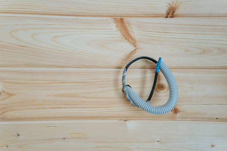 A flexible hose is securely attached to an electrical wire that is mounted on a wooden wall, showcasing the intricate connection and functionality of both components within the structureの写真素材
