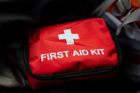 A bright red first aid kit that features a distinct white cross on its exterior, making it easily recognizable as a medical emergency supply pack for quick access during urgent situationsの写真素材