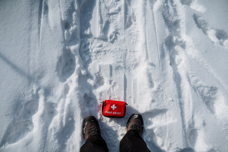 A person is standing in deep, white snow with a wellequipped first aid kit beside them, fully prepared for any emergencies or accidents that could occur while they are out enjoying the winter seasonの写真素材