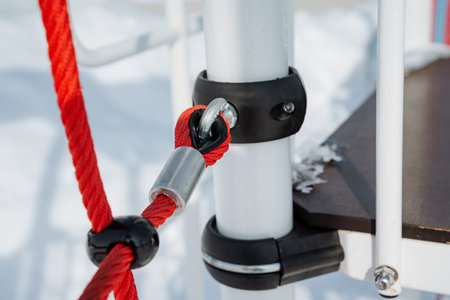 This image captures a closeup of a playground connection a vibrant red rope fastened by a sturdy...