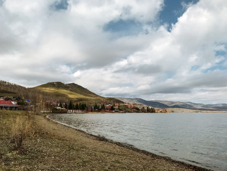 A serene lake surrounded by majestic mountains in the background, with a charming house located right on the shore, creating a picturesque and tranquil scene perfect for relaxationの写真素材
