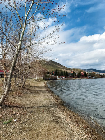A serene lake surrounded by lush trees lining the shore, with majestic mountains rising prominently...