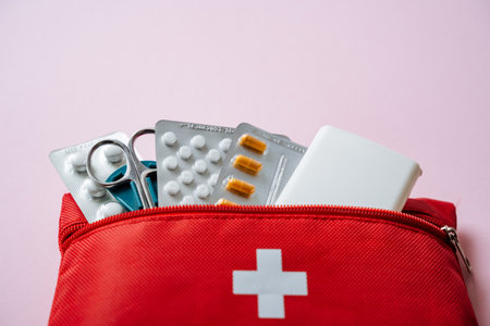 A vibrant red first aid kit that is brimming with essential medical supplies, perfectly showcasing preparedness for health and safety against a warm and inviting soft pink backgroundの写真素材