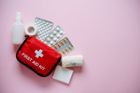 Discover a wide range of essential first aid kit items, including bandages, medications, antiseptics, and more, all showcased against a soft pink background for a comforting lookの写真素材