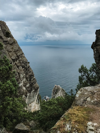 On a cloudy day, you can see a stunning view of the vast ocean stretching far beyond from a high,...