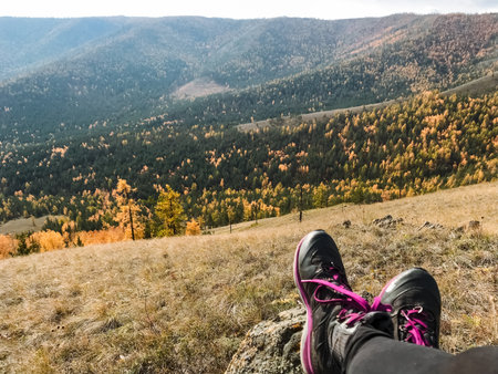 A person finds a comfortable position while relaxing on a picturesque hill, with their feet delightfully in the air, fully savoring the stunning view and the tranquil surroundings surrounding themの写真素材