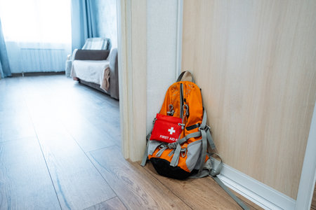 A cozy living room feels warm and inviting, with a sturdy backpack, equipped with a first aid kit, leaning against the wall for reassurance and safety for all guests and familyの写真素材