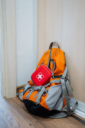 A robust and sturdy backpack sits on a rustic wooden floor, containing a fully stocked first aid...