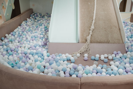In the center of a colorful ball pit brimming with an assortment of vibrant balls, there exists a...