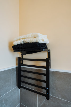 There is a towel rack set up in the bathroom, and perched atop this rack is a neatly arranged stack of towels, ready for use or display. Its a simple yet functional addition to the spaceの写真素材