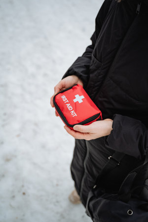 A person is firmly gripping a bright red first aid kit, ready and fully equipped to swiftly assist any individuals who may require help or medical attention during an emergency situationの写真素材