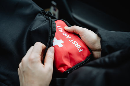 Expert hands quickly grab a bright red first aid kit from a spacious black bag in a vehicle,...