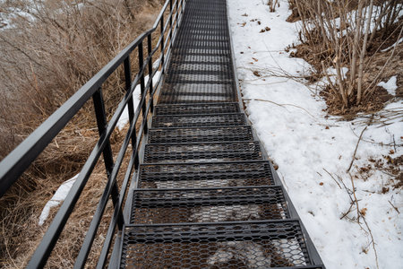 A set of stairs leading up toward a snowy hillside. The stairs include a sturdy handrail for safety as you navigate the freezing conditionsの写真素材