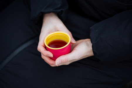 An individual is gently holding a warm cup of tea in their hands, savoring the aroma and warmth it brings, feeling its comforting presence as they prepare to enjoy this delightful beverageの写真素材