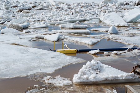A yellow boat floats in a large puddle, surrounded by thick ice, creating a vivid contrast against the cold winter landscape, enhancing its vibrant color and capturing winters essenceの写真素材