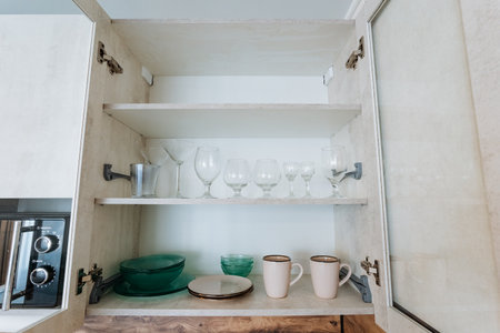 A kitchen cabinet that is filled to the brim with a variety of plates, cups, and glasses of all...
