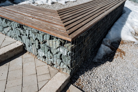 A beautifully crafted, sturdy wooden bench is placed atop a solid stone wall, seamlessly blending...