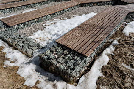 A sturdy wooden bench is resting on a carefully arranged pile of rocks, providing a perfect spot to relax and enjoy natures beauty while being surrounded by rustic elements of the settingの写真素材