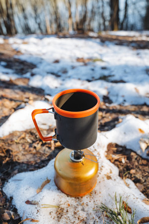A steaming cup of rich coffee rests on an old, vintage stove, surrounded by fluffy, pristine white snow, creating a wonderfully cozy scene that beautifully contrasts the heat and the coldの写真素材