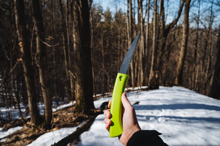 A person is currently gripping a green saw firmly in their hand while being surrounded by the...