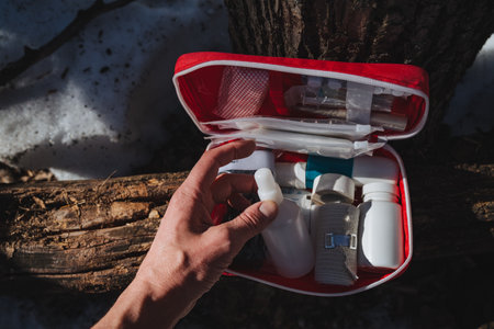 A person is holding a first aid kit tightly in their hand, which is essential for providing immediate medical assistance when needed, ensuring safety in case of injuries or emergenciesの写真素材