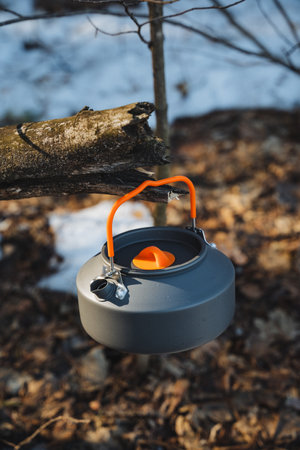 A portable camping kettle hangs from a tree branch, highlighting its efficient design. Its ideal for outdoor adventures, camping trips, and minimalist cooking in natureの写真素材