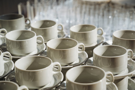 On a table, there is a collection of white coffee cups along with matching saucers, arranged neatly to create a visually appealing display of tableware and serveware for enjoying beveragesの写真素材