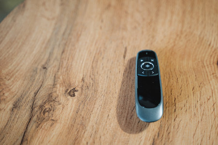 A sleek and modern remote control elegantly rests on a beautifully crafted wooden table, truly exemplifying the perfect and harmonious blend of advanced technology combined with natural materialsの写真素材
