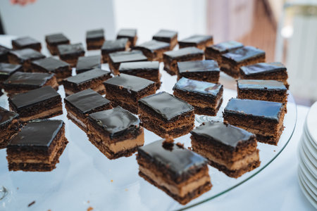 On a beautifully arranged table rests a tray filled with delicious chocolate cakes, elegantly displayed on a glass plate, enticing anyone who passes by with the promise of a sweet treatの写真素材