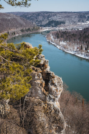 Imagine standing on a cliff, gazing at a winding river flowing through vibrant landscapes, surrounded by towering mountains and rugged rocks, embodying natures beauty and tranquilityの写真素材
