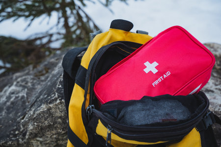 A vibrant yellow backpack along with a compact red first aid kit are absolutely essential for effectively managing emergencies during outdoor adventures and extended trips in various environmentsの写真素材