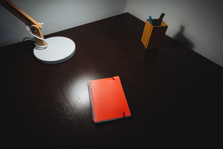 An elegant desk that features a stylish lamp and a neatly arranged notebook creates a delightful,...