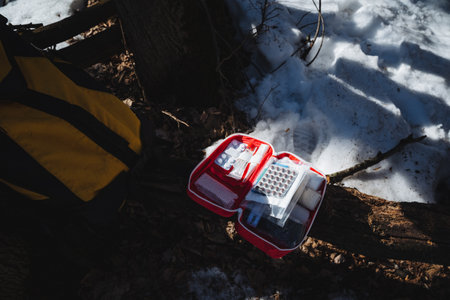 A first aid kit is currently positioned on the snowy ground, visibly contrasting against the white...