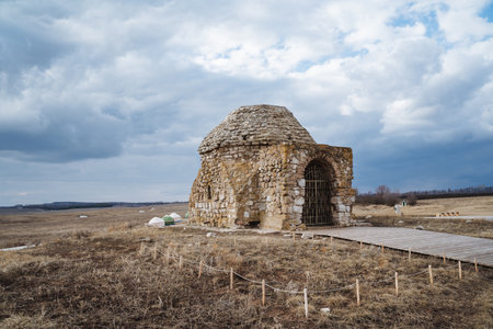 In a serene field, a small yet charming stone structure captures the essence of the landscape's beauty while embodying the profound and historic significance of the surrounding areaの写真素材