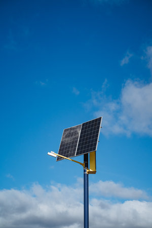 A solar panel that is mounted securely on a pole, with a vast blue sky beautifully displayed in the background, showcasing the importance of renewable energy sources and their applicationsの写真素材