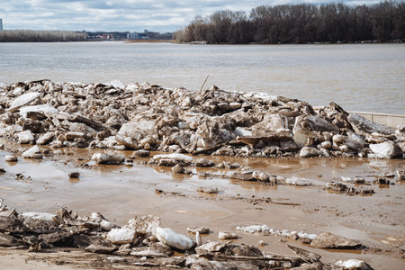 A substantial and sizable pile of various rocks is currently positioned on the bank of a river, creating an interesting landscape along the shoreline that is both natural and rugged in appearanceの写真素材