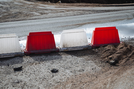 A continuous row of bright red and white barriers is positioned along the side of a road, making it...