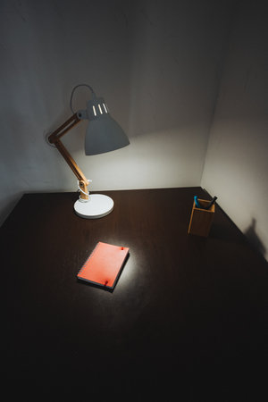 A desk with a lamp and a notebook on itの写真素材