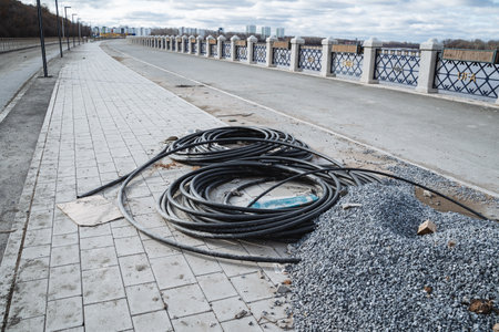 A large and diverse assortment of various wires is casually strewn across the pavement beside a sizable heap of gravel, creating a somewhat disorganized and chaotic scene when viewed from a distanceの写真素材